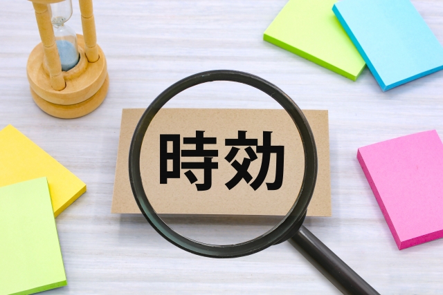 Magnifying glass over a card with the Chinese word 时效, on a desk with colorful sticky notes, conveying a focus on timeliness.